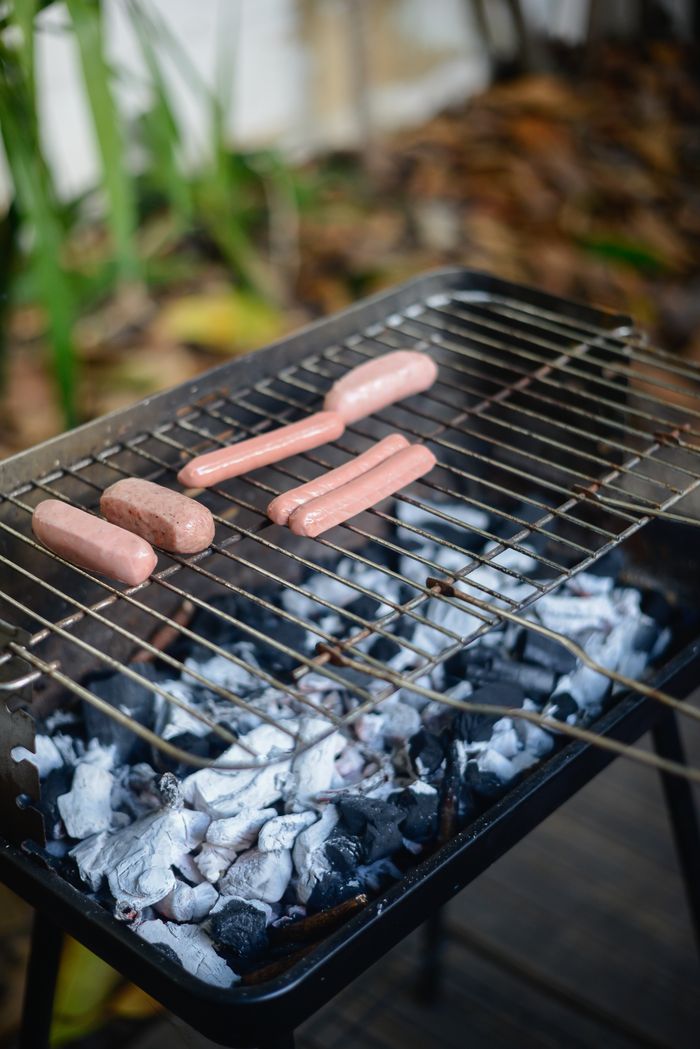 Close-up of hotdogs roasting on a charcoal grill outdoors in Portugal.